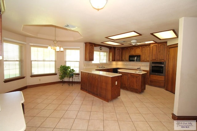 kitchen featuring stainless steel oven, light tile patterned floors, a raised ceiling, pendant lighting, and a kitchen island