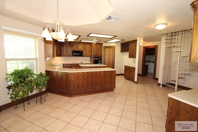 kitchen with kitchen peninsula, wall oven, light tile patterned floors, an inviting chandelier, and hanging light fixtures