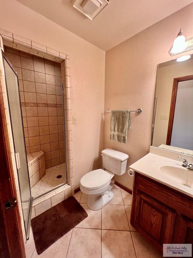 bathroom featuring tile patterned floors, vanity, toilet, and an enclosed shower