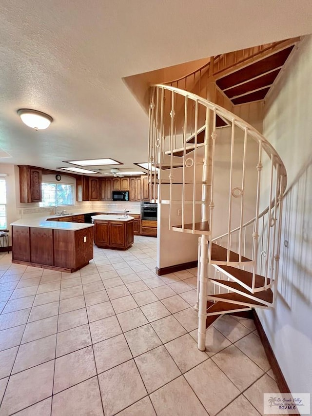 kitchen featuring wall oven, sink, light tile patterned floors, and hanging light fixtures