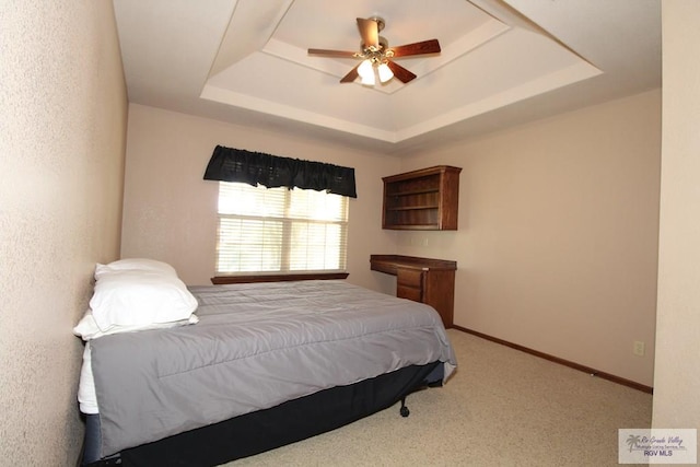 carpeted bedroom featuring a tray ceiling and ceiling fan