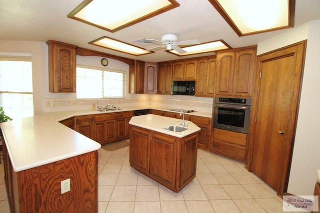 kitchen with stainless steel oven, a center island with sink, sink, stovetop, and kitchen peninsula