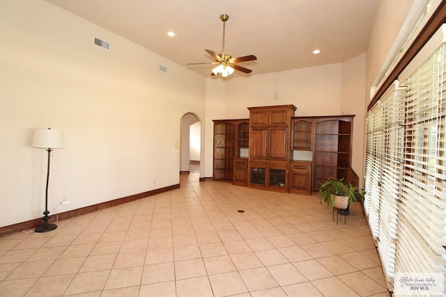 unfurnished living room featuring ceiling fan, light tile patterned floors, and a towering ceiling