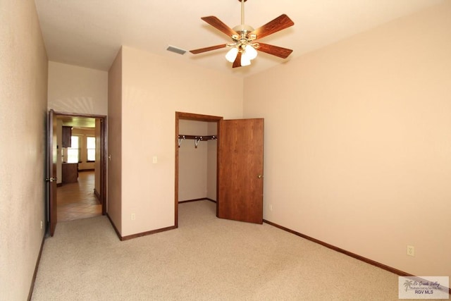 unfurnished bedroom featuring ceiling fan, a walk in closet, light carpet, and a closet