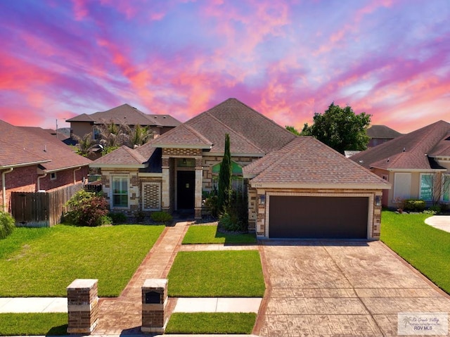 view of front of house featuring an attached garage, fence, driveway, a yard, and stone siding