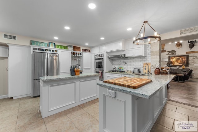 kitchen with decorative light fixtures, a center island, white cabinetry, and appliances with stainless steel finishes