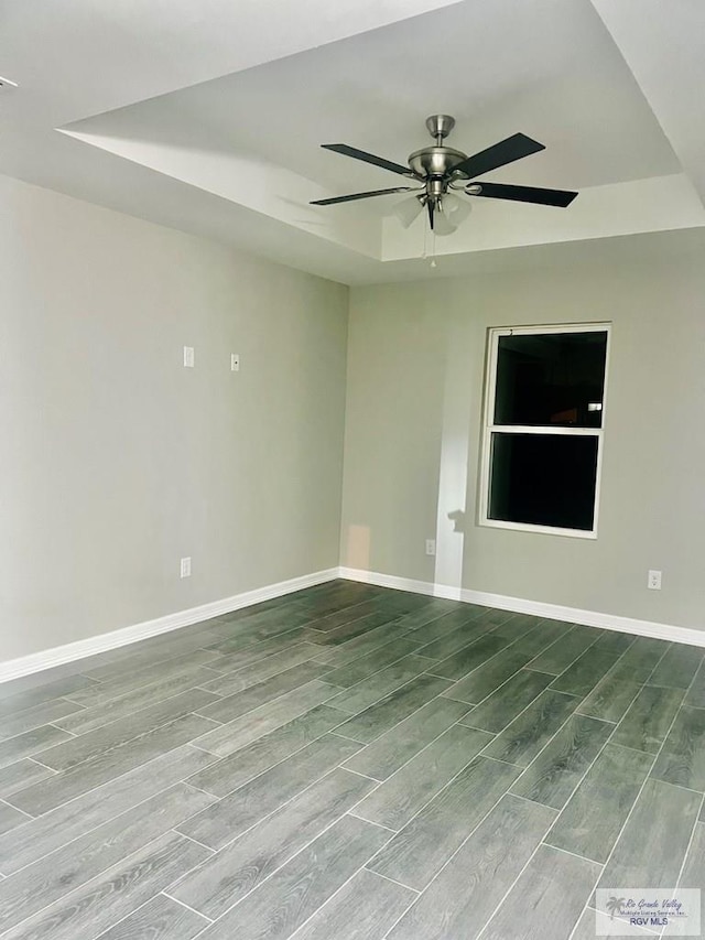 empty room with hardwood / wood-style flooring, ceiling fan, and a raised ceiling