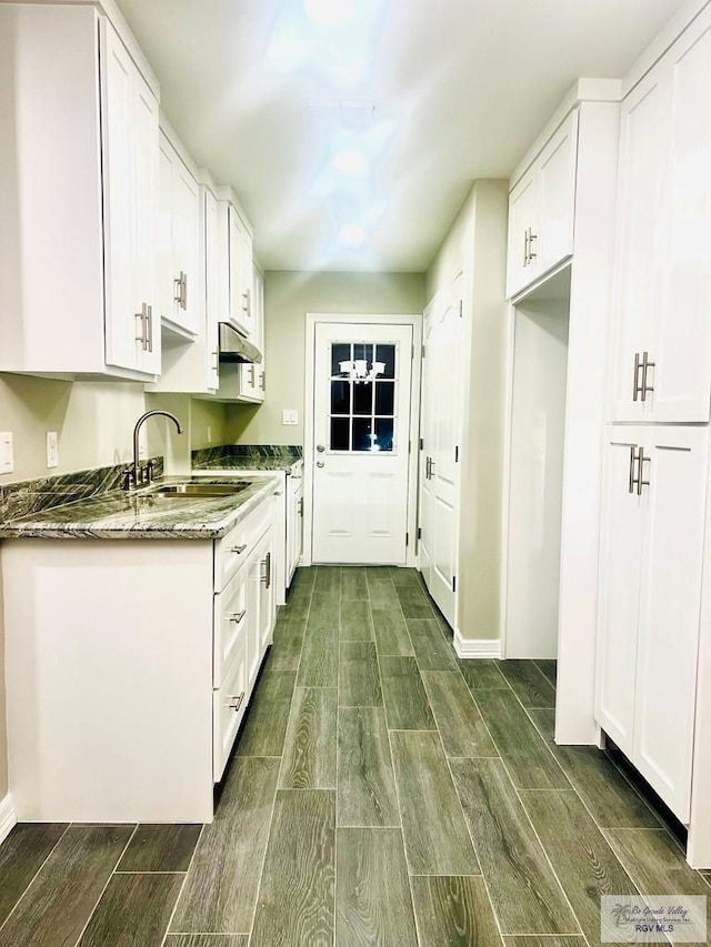 kitchen featuring dark stone countertops, sink, and white cabinets