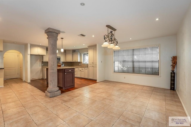 kitchen with decorative backsplash, a center island, light tile patterned flooring, and decorative light fixtures