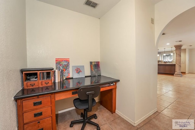 home office with built in desk, light tile patterned floors, and decorative columns