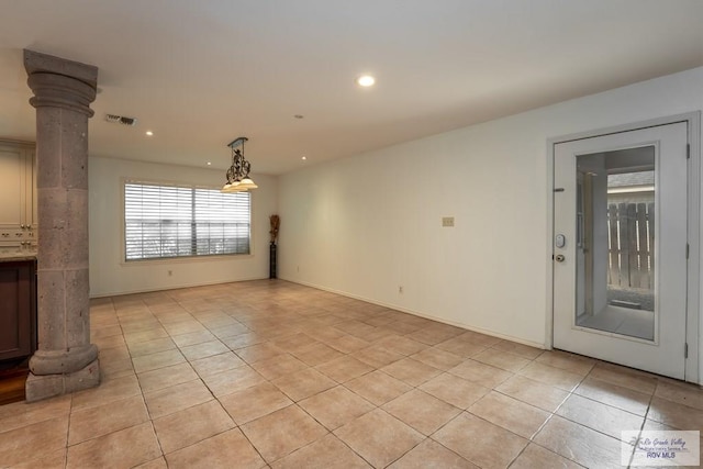 unfurnished living room with decorative columns and light tile patterned flooring