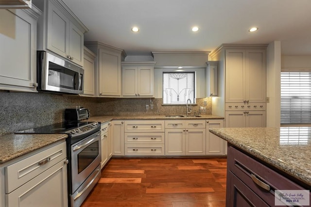 kitchen featuring light stone countertops, sink, dark hardwood / wood-style flooring, decorative backsplash, and appliances with stainless steel finishes