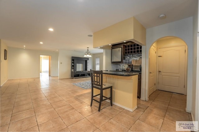 kitchen featuring light tile patterned floors, an inviting chandelier, decorative light fixtures, a breakfast bar area, and a kitchen island