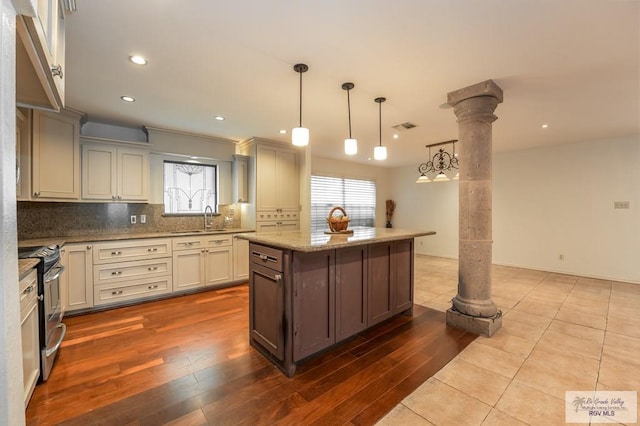 kitchen featuring plenty of natural light, decorative light fixtures, ornate columns, and stainless steel electric range oven