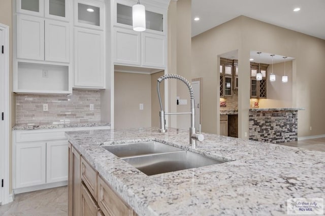 2402 S Christian Cir, Harlingen, TX 78550 - kitchen featuring decorative backsplash, pendant lighting, glass insert cabinets, recessed lighting, and light stone counters