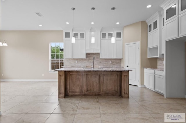 2402 S Christian Cir, Harlingen, TX 78550 - kitchen featuring light marble finish floors, backsplash, a center island with sink, white cabinets, and recessed lighting