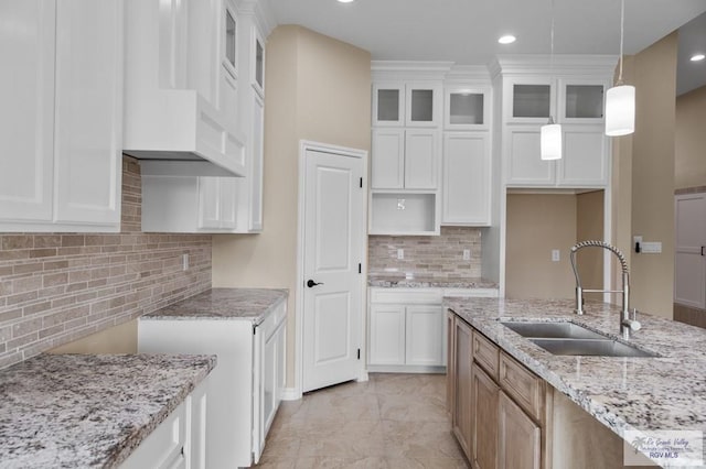 2402 S Christian Cir, Harlingen, TX 78550 - kitchen featuring light stone countertops, backsplash, glass insert cabinets, hanging light fixtures, and white cabinets