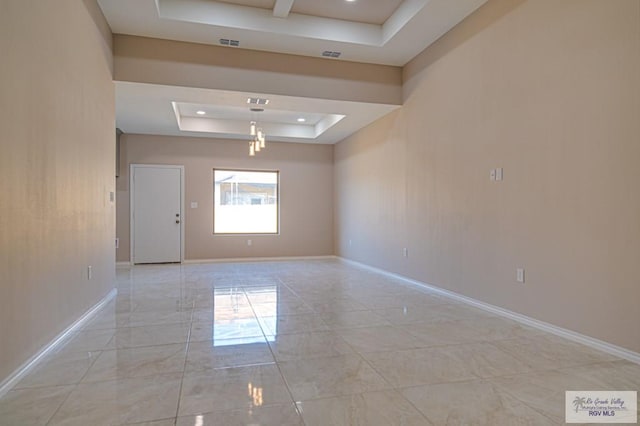 empty room featuring marble finish floor, visible vents, baseboards, and a raised ceiling