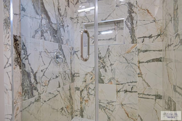 bathroom featuring a marble finish shower