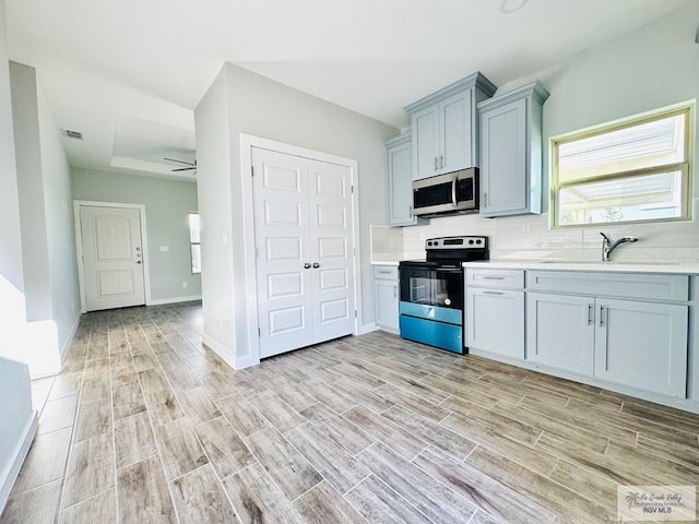 kitchen featuring ceiling fan, sink, light wood-type flooring, and appliances with stainless steel finishes