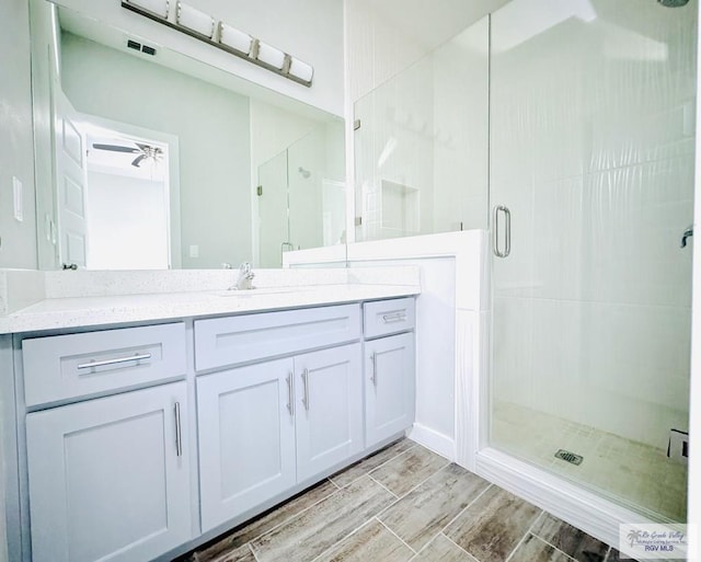 bathroom with ceiling fan, vanity, and a shower with shower door