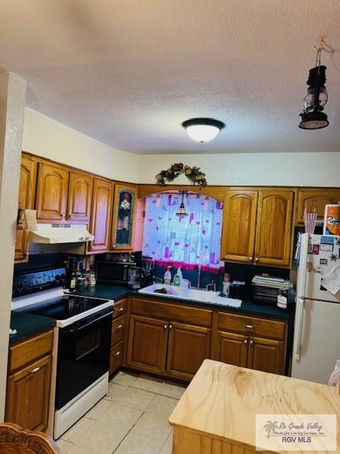 kitchen with a textured ceiling, white appliances, light tile patterned floors, and sink