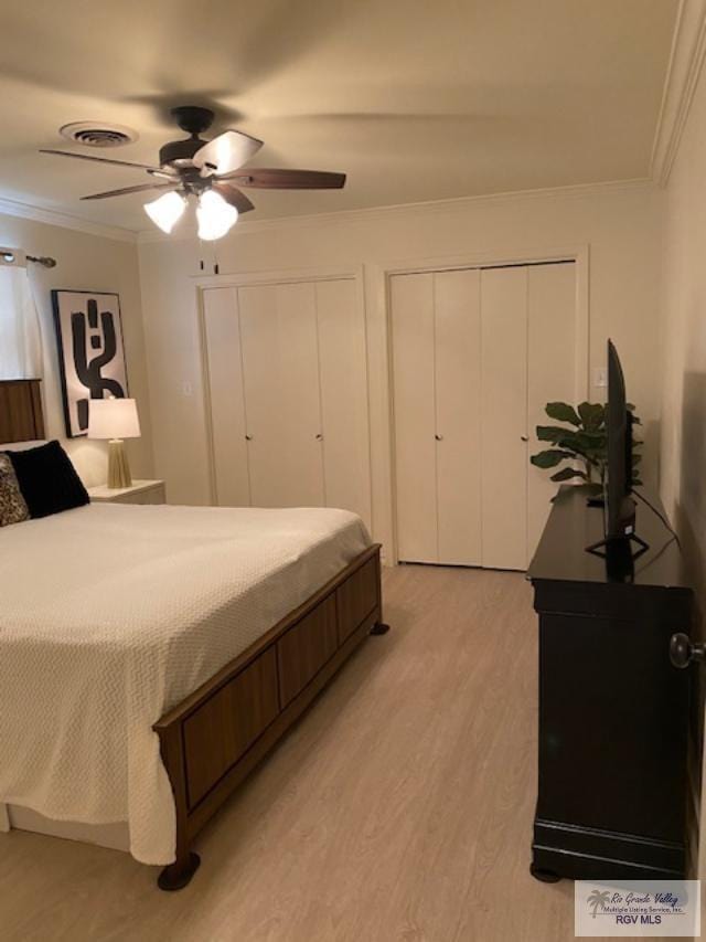 bedroom with ceiling fan, multiple closets, ornamental molding, and light hardwood / wood-style flooring