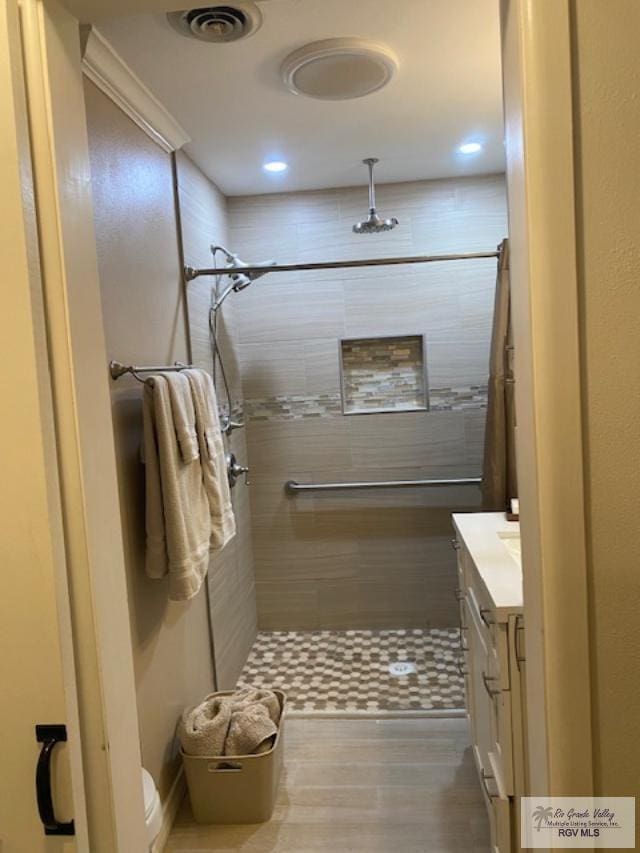 bathroom featuring tiled shower, vanity, and toilet