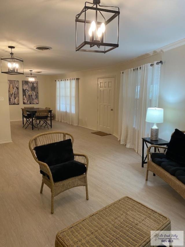 sitting room featuring light hardwood / wood-style floors, a chandelier, and ornamental molding