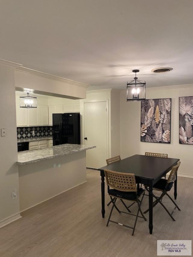 dining room with an inviting chandelier, ornamental molding, and light wood-type flooring