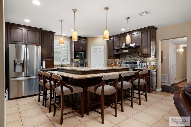 kitchen featuring dark brown cabinets, a center island, stainless steel appliances, and decorative light fixtures