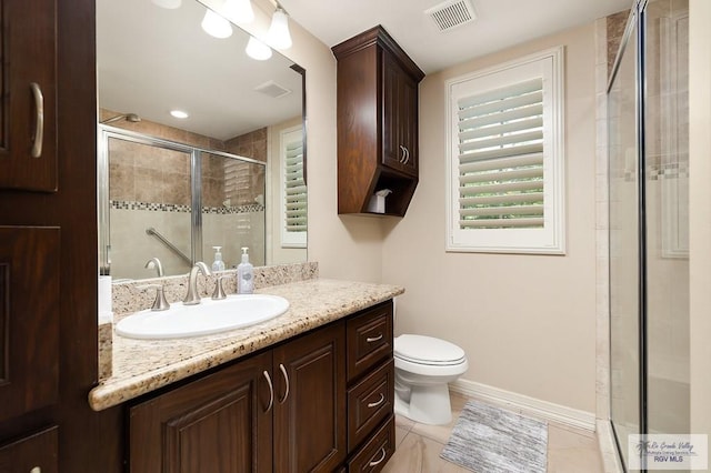 bathroom featuring tile patterned floors, vanity, a shower with shower door, and toilet