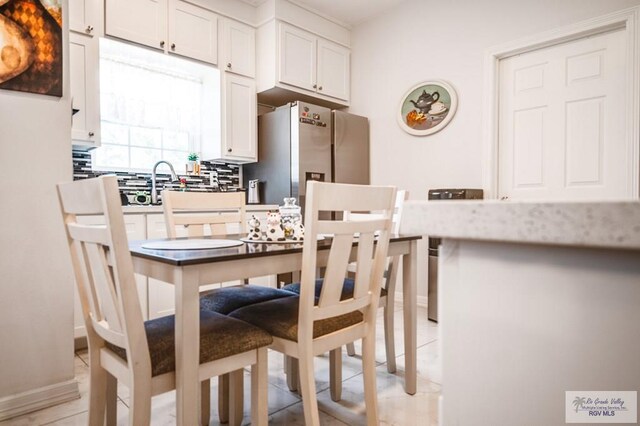 kitchen with decorative backsplash, white cabinetry, and stainless steel refrigerator