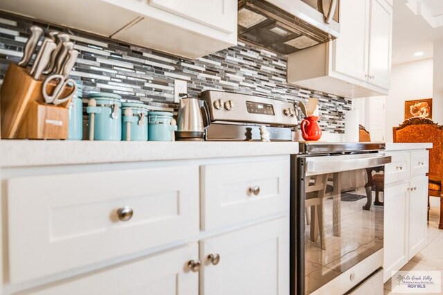 kitchen with white cabinets, light tile patterned flooring, appliances with stainless steel finishes, and tasteful backsplash