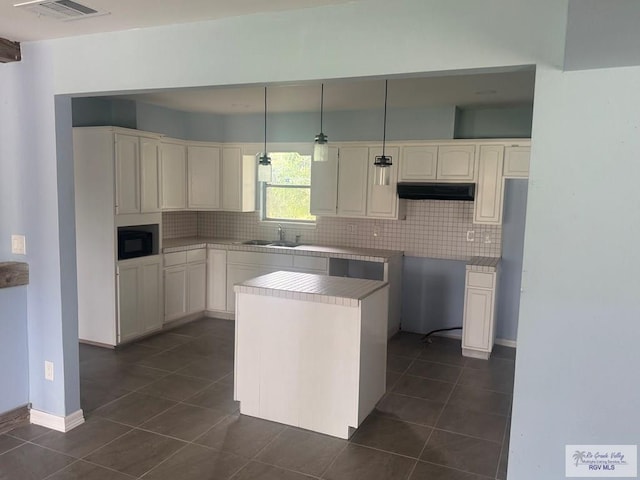 44 Highland Ter, Brownsville, TX 78521 - kitchen with a sink, black microwave, backsplash, and dark tile patterned floors