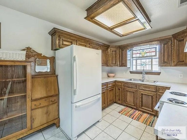 kitchen with sink, white appliances, and light tile patterned flooring