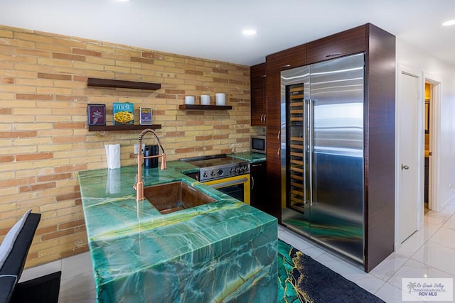 kitchen featuring appliances with stainless steel finishes, light tile patterned floors, a sink, and open shelves