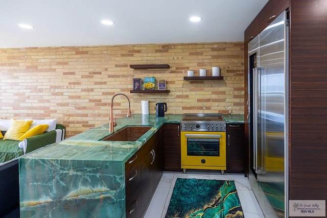 kitchen featuring brick wall, stainless steel appliances, modern cabinets, and a sink