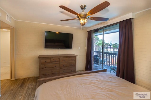 bedroom with access to exterior, crown molding, visible vents, brick wall, and wood finished floors