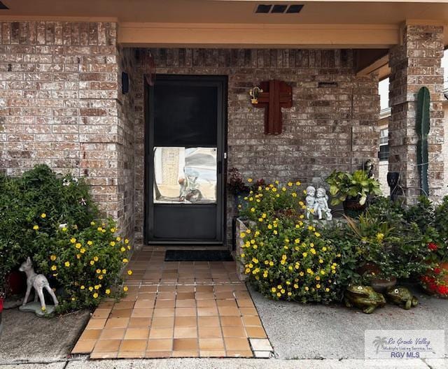 entrance to property featuring brick siding and visible vents