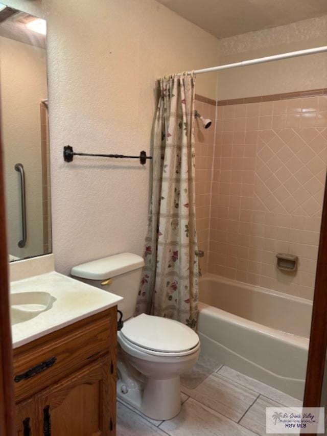 full bath featuring toilet, a textured wall, shower / bath combo with shower curtain, and vanity