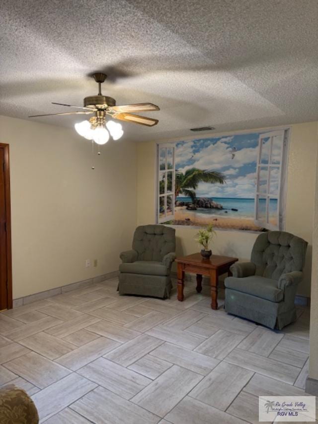 sitting room featuring a ceiling fan, visible vents, a textured ceiling, and baseboards