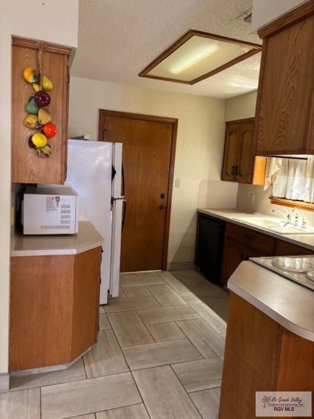 kitchen with black dishwasher, light countertops, and a sink