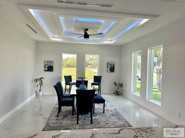 dining room with marble finish floor, a tray ceiling, and a wealth of natural light