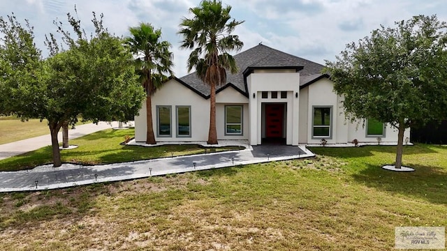 view of front of property with a shingled roof, a front yard, and stucco siding