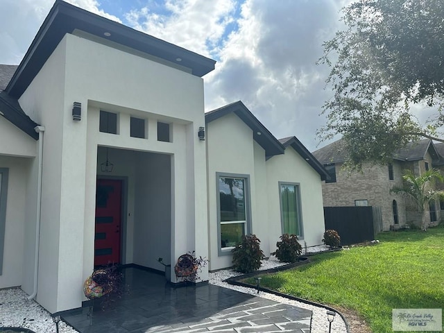 rear view of house featuring a yard and stucco siding