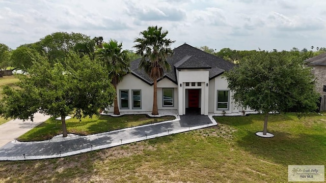 view of front of house with a shingled roof, a front yard, and stucco siding