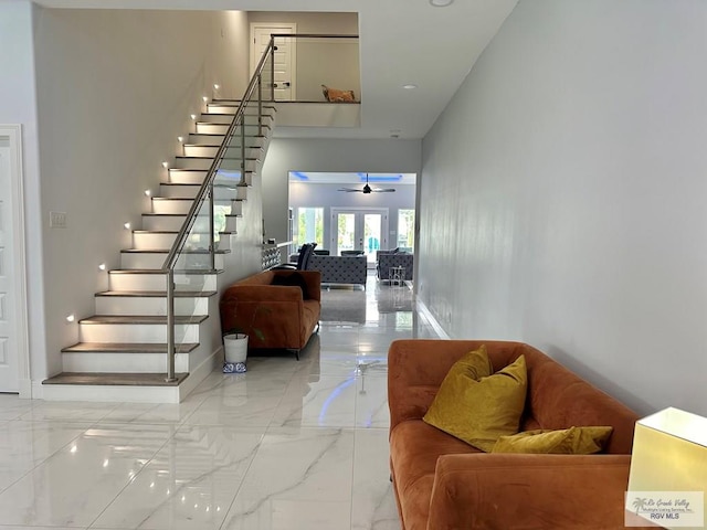 staircase featuring baseboards, a ceiling fan, marble finish floor, a high ceiling, and french doors