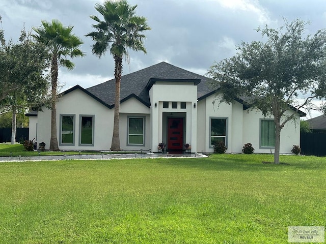 view of front facade with roof with shingles, a front lawn, and stucco siding