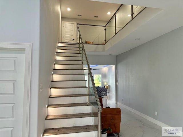 staircase with recessed lighting, marble finish floor, and baseboards